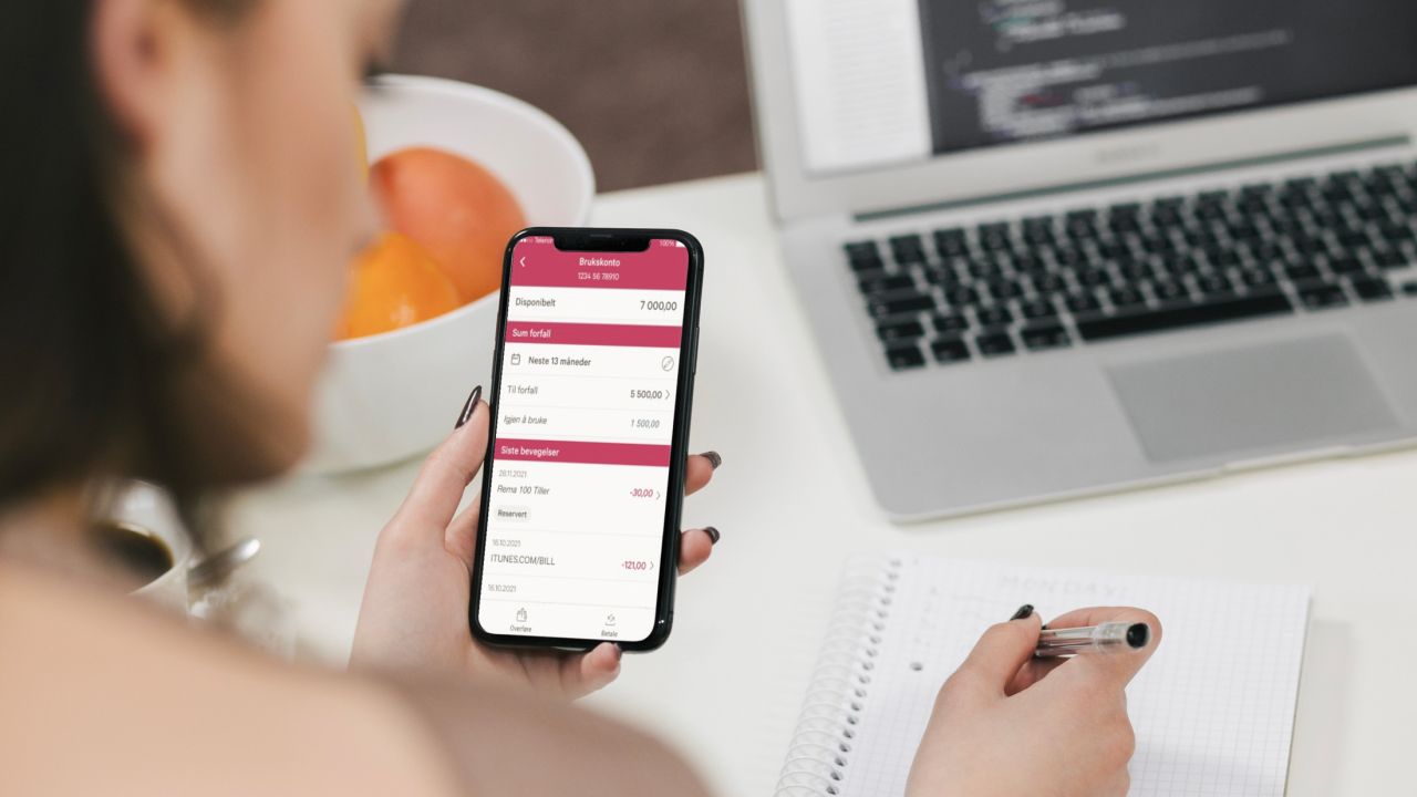 Person sitter ved skrivebord og noterer i kladdebok fra mobilbanken