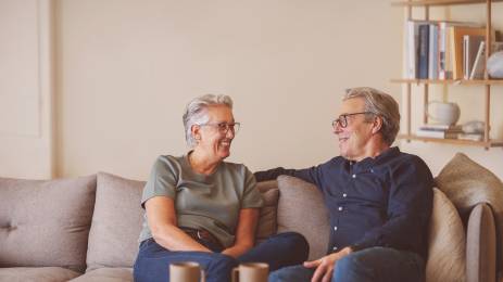 Smilende voksent par i sofa med kaffekopper på bordet