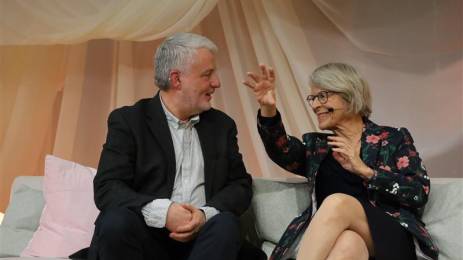 En mann og en kvinne sitter i en sofa og snakker sammen