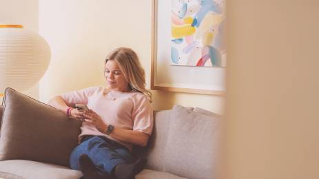 Kvinne i sofa med mobil i hånden