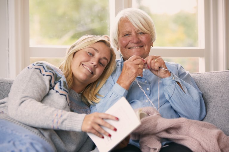 Bestemor og barnebarn koser seg sammen inne i en sofa.