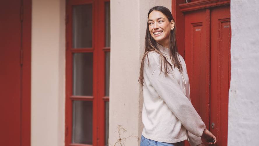 Ung kvinne smiler og låser seg inn en rød inngangsdør