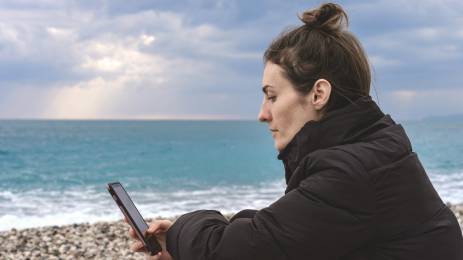 Dame med mobil på stranden