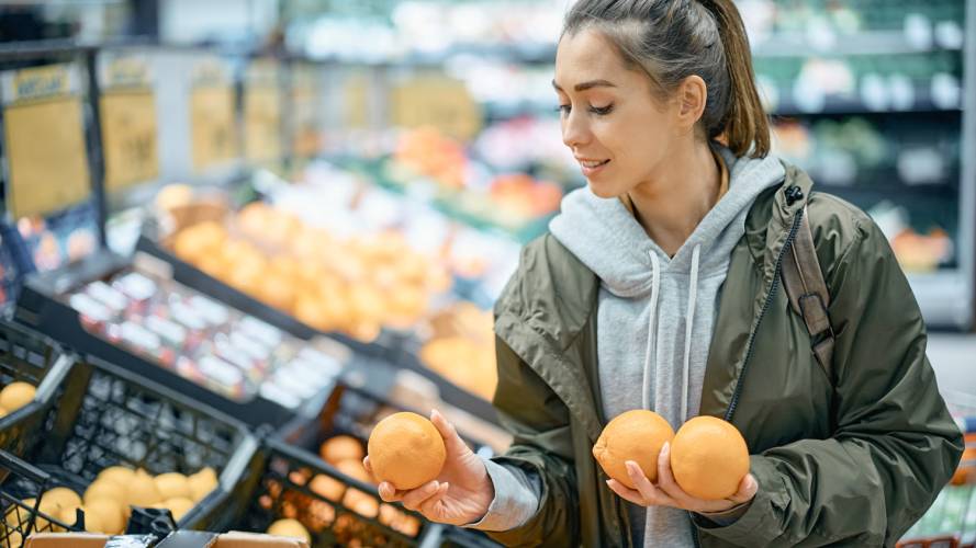 Dame som holder i appelsiner i matvarebutikk
