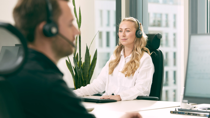 Ung dame som jobber sitter ved pult med headset