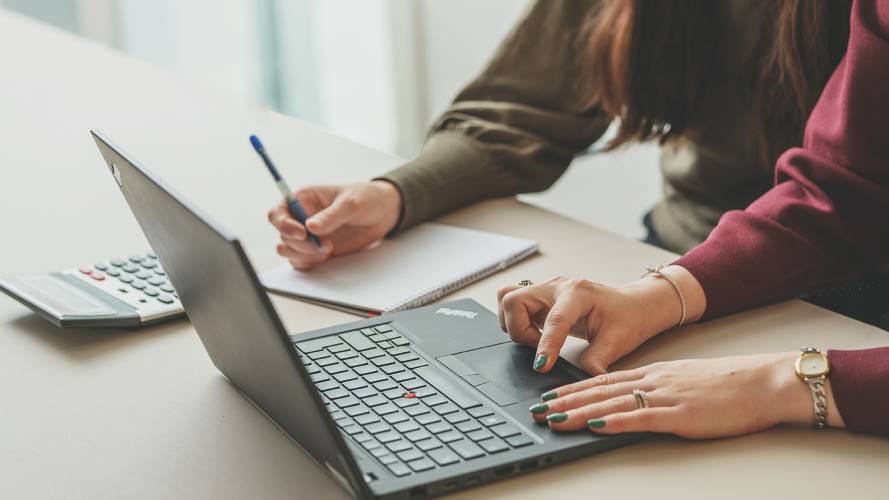 To damer som sitter med pc og skriveblokk