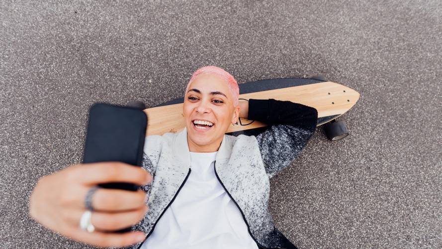 Gutt på skatebord tar selfie med telefonen.