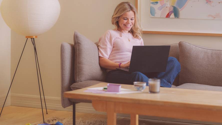 Kvinne i sofa med laptop i fanget