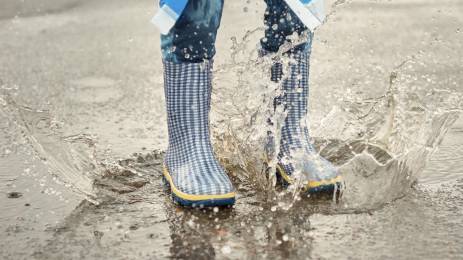 Regnstøvler som hopper i en vannpytt