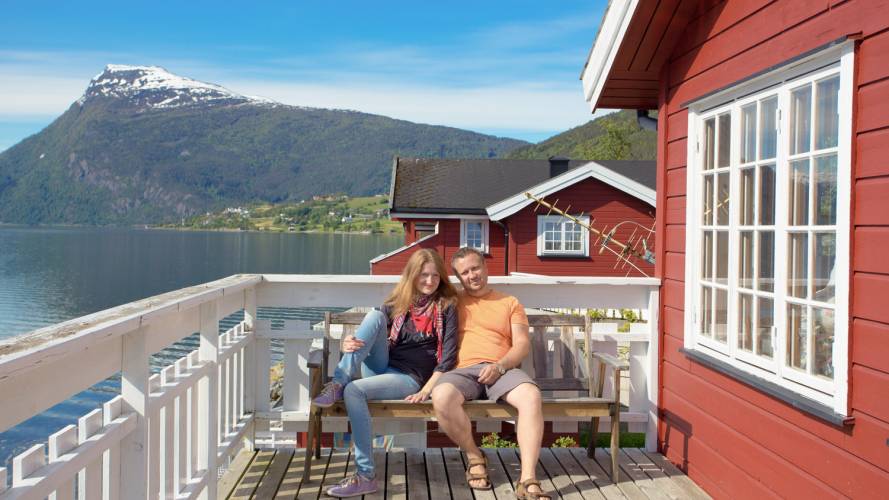 Mann og dame som sitter sammen på terassen med fjord og fjell i bakgrunnen