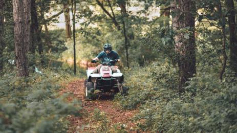 Ung mann som kjører ATV i skogen