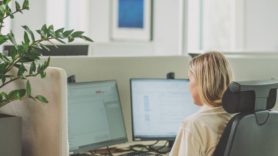 Dame som sitter på et kontor og jobber på pc