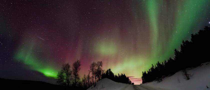 Nordlys over vintervei opp på fjellet